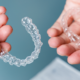 Gros plan sur des mains tenant des aligneurs dentaires transparents, utilisés pour l'orthodontie invisible.